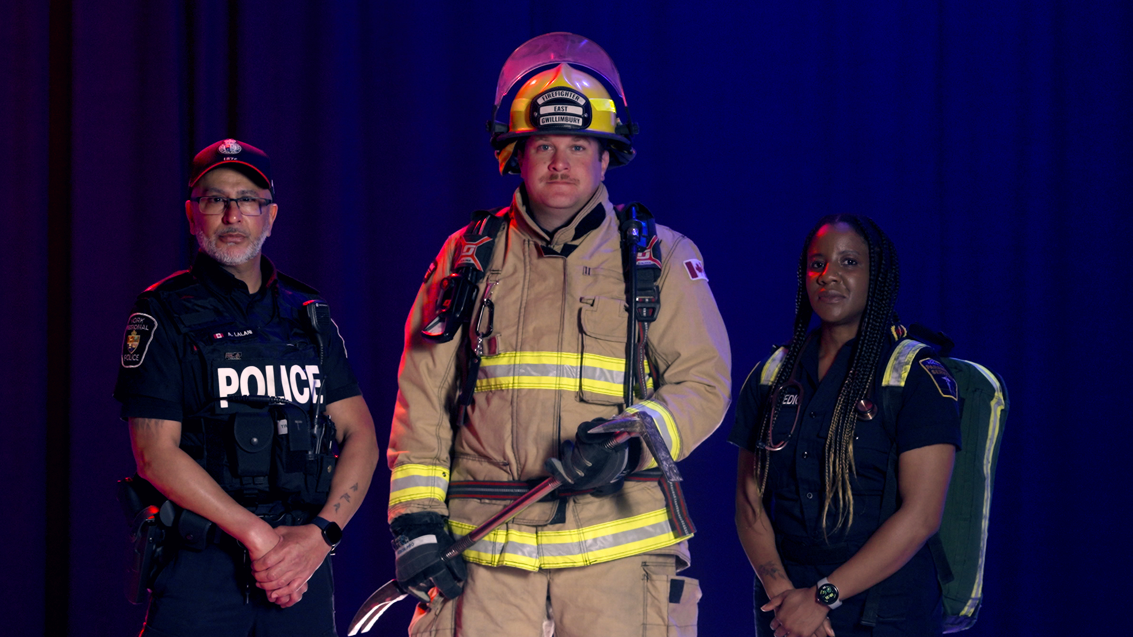 Experience the Career A male police officer, a male firefighter and a female paramedic pose against a blue backdrop
