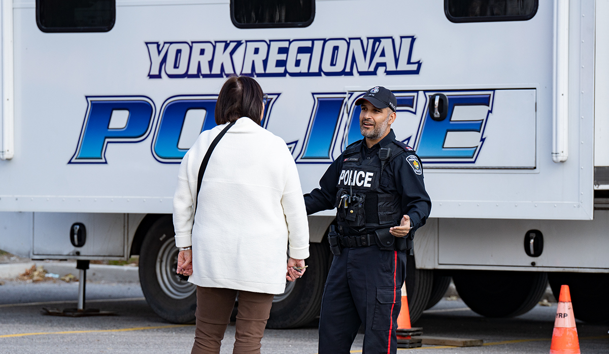 An officer speaks to someone next to a trailer that reads YORK REGIONAL POLICE